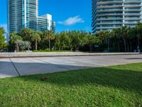 an empty area in front of a large residential building, surrounded by palm trees and greenery