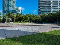 an empty area in front of a large residential building, surrounded by palm trees and greenery