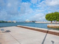 the view of a harbor area next to a dock with a bench, and the sky