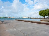 the view of a harbor area next to a dock with a bench, and the sky