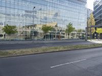 a car parked at an intersection and an empty street with buildings in the background glass, surrounded by green grass