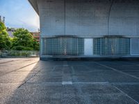 two empty parking spaces with two empty doors and a large window on the wall between two buildings