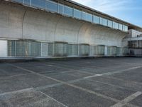 two empty parking spaces with two empty doors and a large window on the wall between two buildings