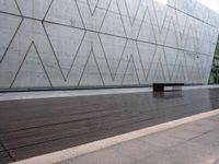 a bench is on the wooden floor in front of a large concrete wall at the park