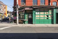 the side street corner with a bench in front of a building and a few cars parked at the intersection