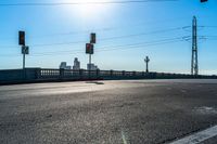 two red stop lights on the corner of a road with a bridge in the distance