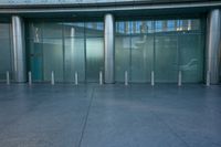 the glass doors of an entrance have white pillars on them and are decorated with stainless poles