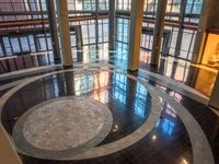 a circular marble floor in front of tall windows in a large building with a clock