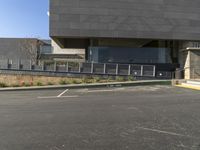 a tall grey building that has multiple windows and steps outside it and a car in front