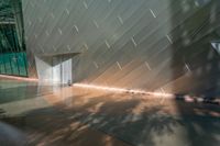 a small fountain and concrete wall in an enclosed room, with sunlight streaming down on it