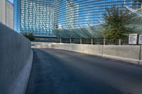 a very empty road near some tall buildings and an office building in the background with blue sky