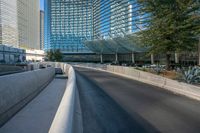 a very empty road near some tall buildings and an office building in the background with blue sky