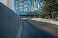 a very empty road near some tall buildings and an office building in the background with blue sky