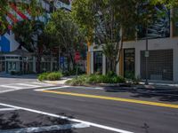 empty street in front of an urban building with trees and a stop sign on a corner