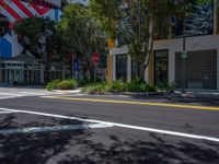 empty street in front of an urban building with trees and a stop sign on a corner