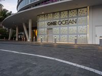 a one ocean store with white lettering and the front lit up at dusk with trees around