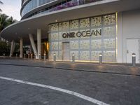 a one ocean store with white lettering and the front lit up at dusk with trees around