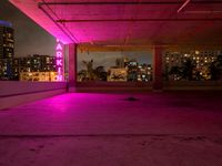 the roof terraced area features a brightly lit sign and graffiti on the concrete, while pink is in the dark