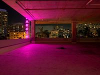 the roof terraced area features a brightly lit sign and graffiti on the concrete, while pink is in the dark