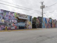 a graffiti building in the center of an intersection in front of the road with power lines