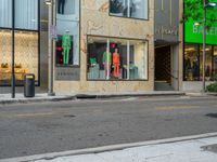 the back of a car drives down a street past a storefront window with clothing displayed in the glass