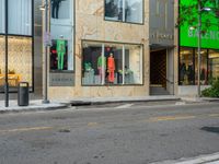 the back of a car drives down a street past a storefront window with clothing displayed in the glass