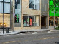 the back of a car drives down a street past a storefront window with clothing displayed in the glass