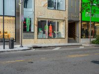 the back of a car drives down a street past a storefront window with clothing displayed in the glass