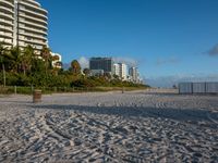 a large white building sitting on the top of a beach next to buildings and trees