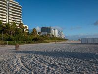 a large white building sitting on the top of a beach next to buildings and trees