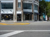 a crosswalk intersection in front of a building with a lot of windows and a person walking across the street