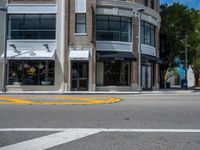 a crosswalk intersection in front of a building with a lot of windows and a person walking across the street