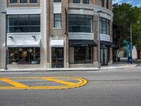 a crosswalk intersection in front of a building with a lot of windows and a person walking across the street