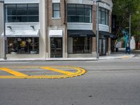 a crosswalk intersection in front of a building with a lot of windows and a person walking across the street