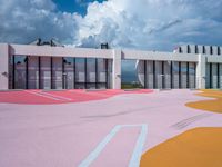 a bright painted court outside a building with lots of windows and pink paint on the ground