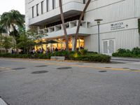 a street view of an asian american hotel or apartment building, and people sitting on the sidewalk