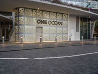 the facade of a building with the words one ocean on it at night time and a street corner