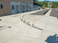 a parking lot that has posts in it along the side of a building with a street