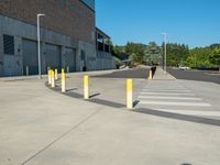 a parking lot that has posts in it along the side of a building with a street