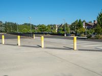 a parking lot that has posts in it along the side of a building with a street