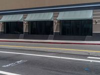 a store front and its windows and street markings on the pavement along with a parking meter, with a blue sign that reads exit only in the street