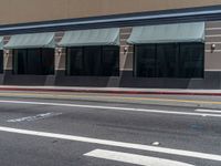 a store front and its windows and street markings on the pavement along with a parking meter, with a blue sign that reads exit only in the street