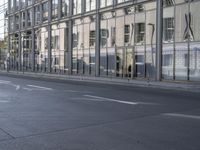 a large building is reflected in the side of the street that goes along this narrow road