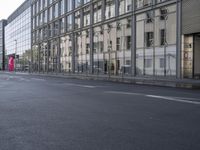 a large building is reflected in the side of the street that goes along this narrow road