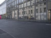 a large building is reflected in the side of the street that goes along this narrow road