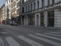 a car passes by in a city street and an apartment building is behind it near the corner of a busy road