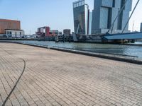 a building next to the ocean with large, tall buildings in the background and a bike parked next to it