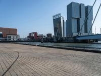 a building next to the ocean with large, tall buildings in the background and a bike parked next to it