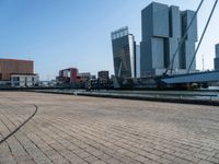 a building next to the ocean with large, tall buildings in the background and a bike parked next to it