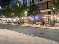 outdoor seating and tables along a walkway at night on a city street in the fall